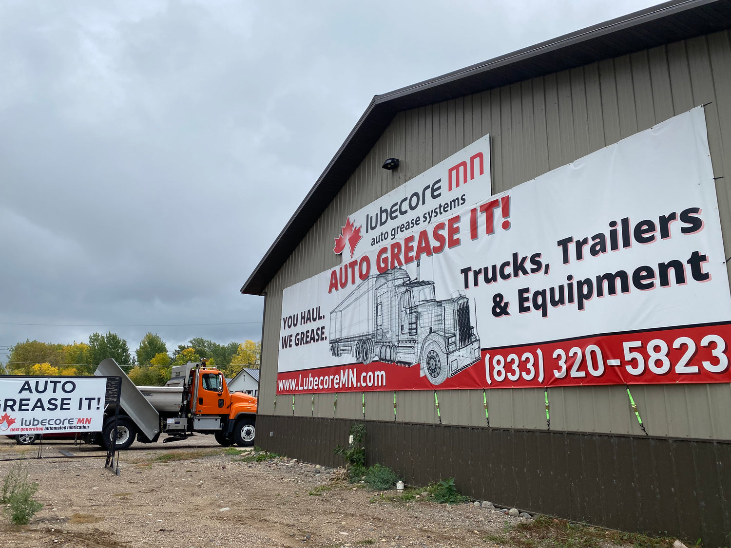 A banner with Lubecore MN's logo and a truck, reading "Auto Grease It! You Haul, We Grease."
